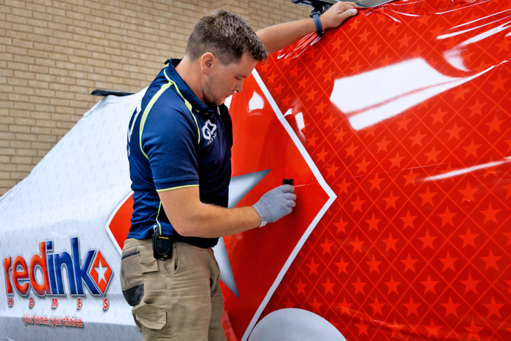 Staff Vehicle Signage Go Graphics VEHICLE SIGNAGE: YOUR QUESTIONS ANSWERED 4 Signage Installer installing Red Ink Homes vehcile wrap onto ute in Go Graphics workshop