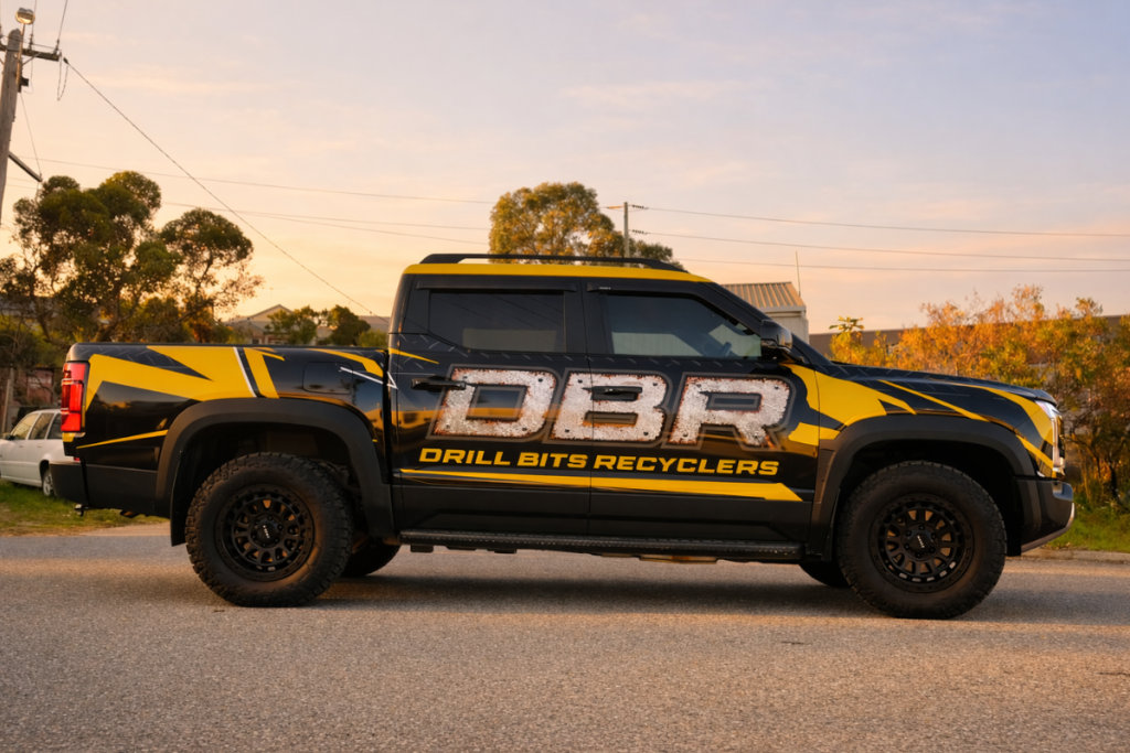 Vehicle Signage Go Graphics DBR VEHICLE SIGNAGE: YOUR QUESTIONS ANSWERED 1 BYD Ute parked in Perth street at dusk featuring full vehicle wrap showcasing Drill Bit Recyclers branding