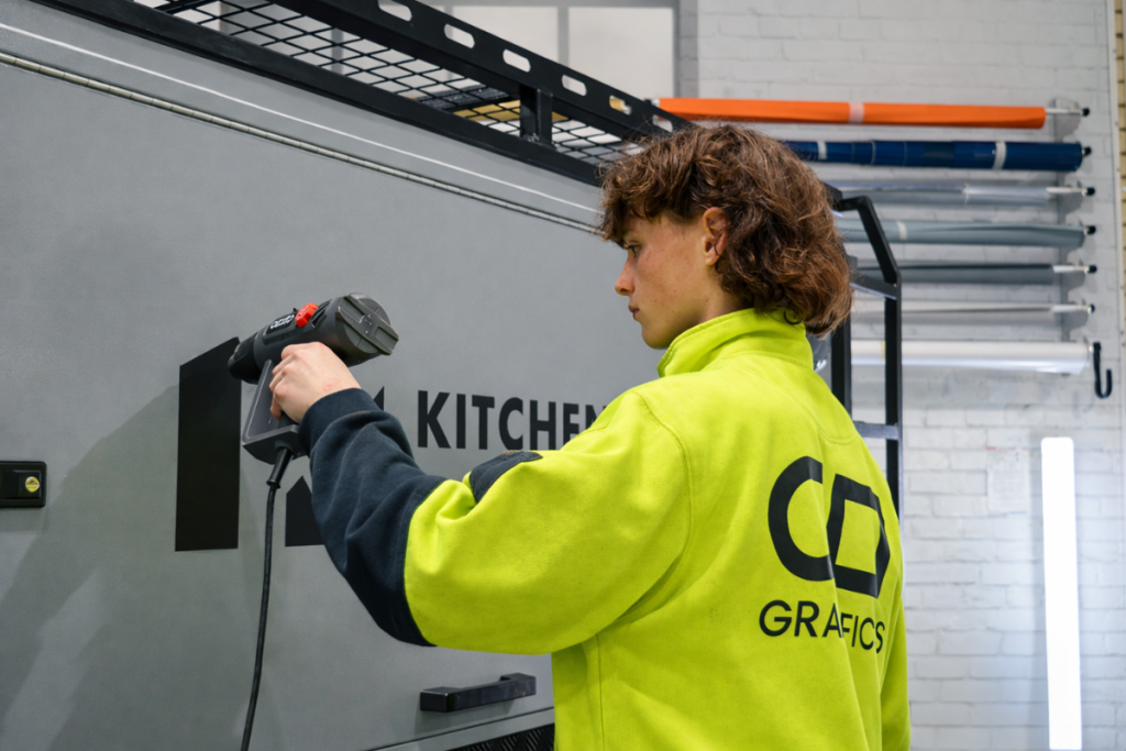 Vehicle Signage Go Graphics Staff VEHICLE SIGNAGE: YOUR QUESTIONS ANSWERED 7 Signage installer installing vehicle graphics in Perth workshop